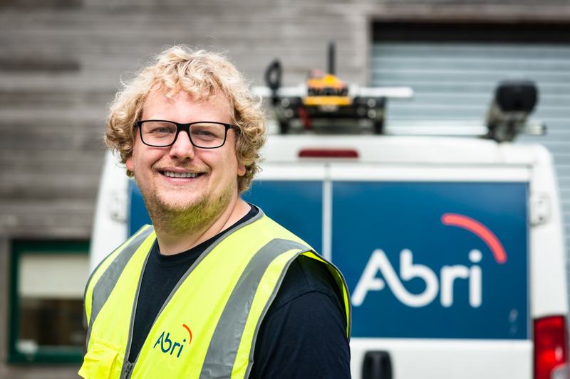 An Abri tradesman looking at the camera, stood in front of an Abri van