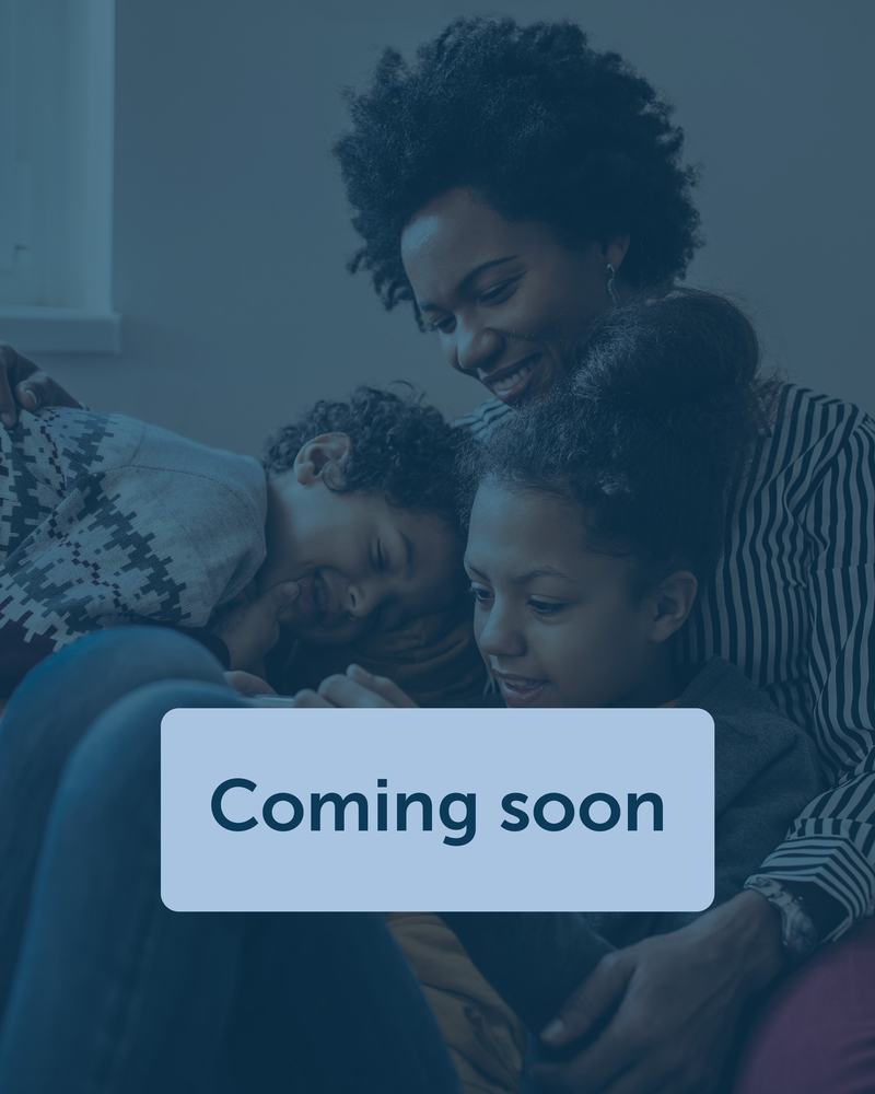 A woman and two children sat together on a sofa and laughing.