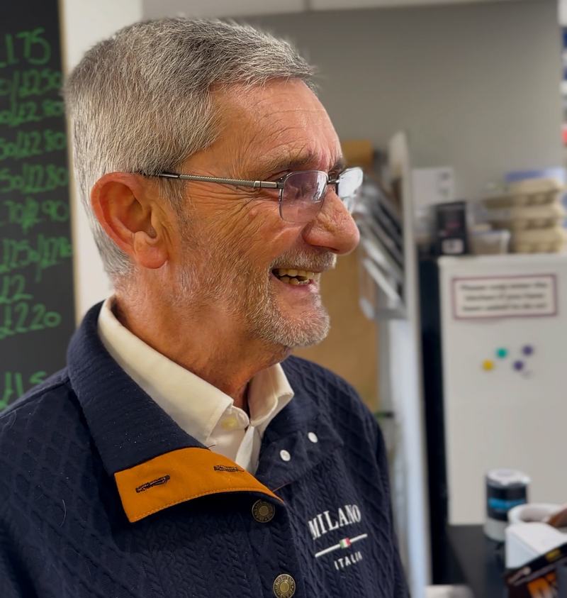 Man facing right and smiling as he orders something at the cafe till