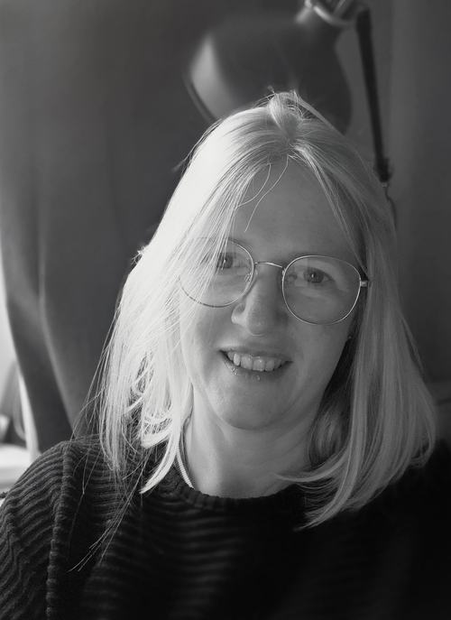 A portrait image of Sophie Clark in black and white. She is smiling and looking at the camera.